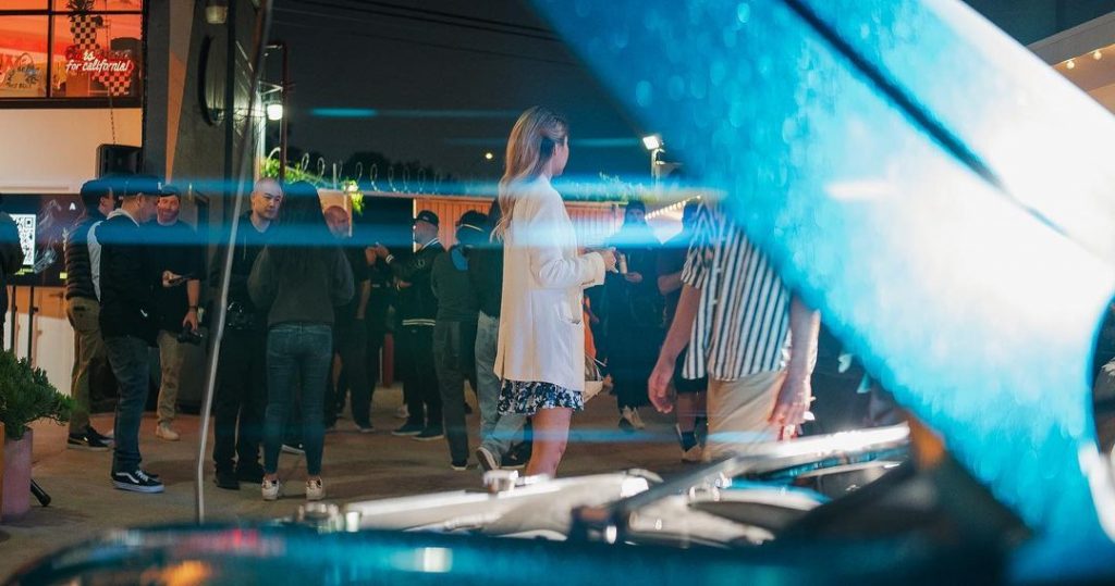 Monique at a car show, framed through an open hood